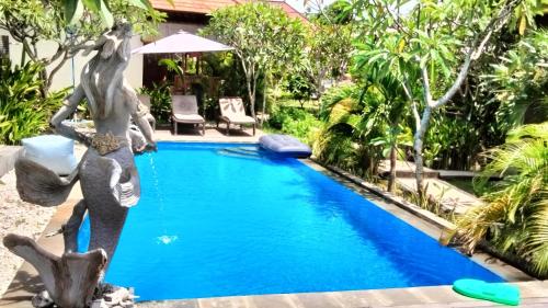 a statue of a mermaid standing next to a swimming pool at Dream Beach Hostel Lembongan in Nusa Lembongan