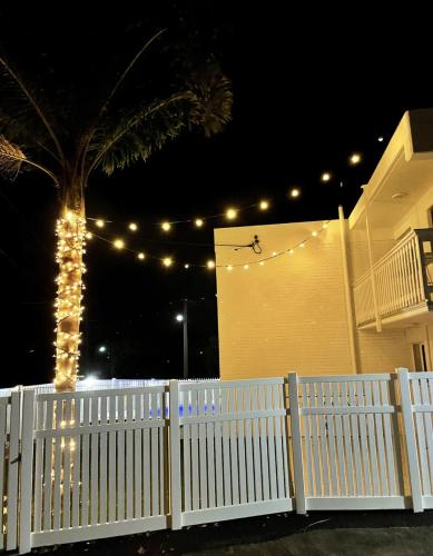 a white fence in front of a house with lights at The Villa's Mooloolaba in Mooloolaba