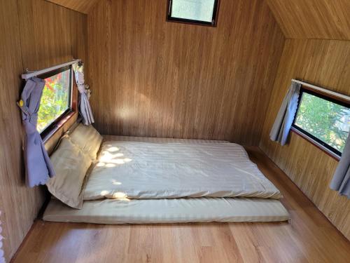 a bed in a small room with two windows at Homestay Bản Búa in Mộc Châu