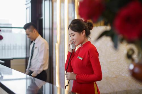 a woman is talking on a cell phone at Mithrin Hotel Halong in Ha Long
