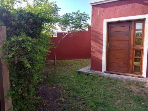 een rood huis met een houten deur in de tuin bij Casa de campo Los Aloe in Cruz del Eje