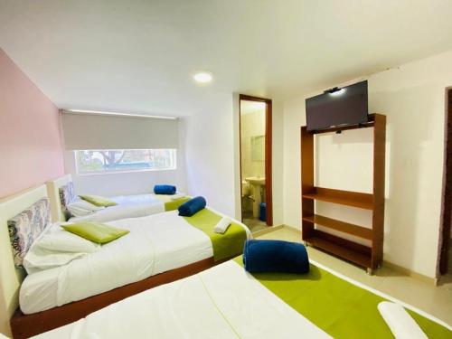1 dormitorio con 2 camas y TV de pantalla plana en Hotel Calantha, en Bogotá