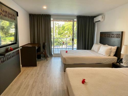 a hotel room with two beds and a balcony at The Pearl South Pacific Resort, Spa & Golf Course in Pacific Harbour
