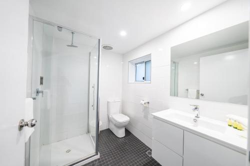a white bathroom with a shower and a toilet at Bega Motel in Bega