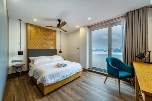 ein Schlafzimmer mit einem Bett und einem blauen Stuhl in der Unterkunft Stay Mikado in Thimarafushi