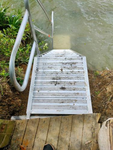 a wooden staircase leading into the water next to the water at Neptune Coastal Haven in Auckland
