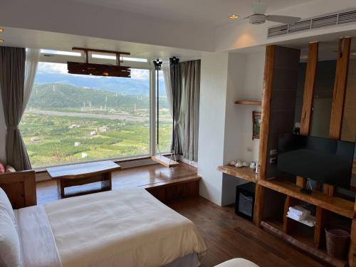 a bedroom with a bed and a large window at Shangrila Leisure Farm in Dongshan