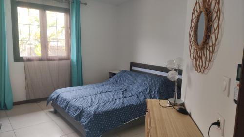 1 dormitorio con cama, mesa y ventana en Mon oasis, en Saint-Louis