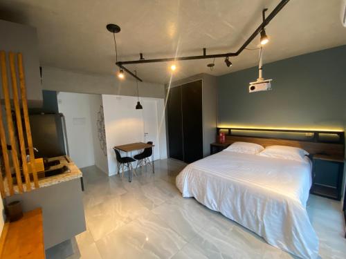 Un dormitorio con una gran cama blanca y una mesa en 58 New studio w/ balcony, fast wifi and movie screen!, en São Paulo