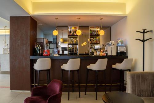 a bar in a restaurant with white stools at Apulia Praia Hotel in Esposende