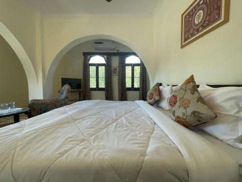 a bedroom with a large white bed with pillows at Sankhu Niwas in Bikaner