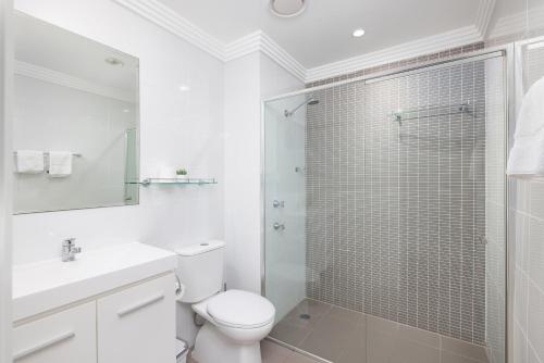 a white bathroom with a toilet and a shower at Aura 10 Shoal Bay in Shoal Bay