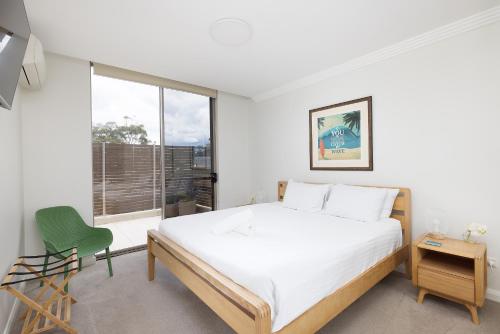 a bedroom with a large bed and a green chair at Aura 10 Shoal Bay in Shoal Bay