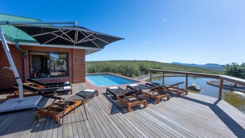 a deck with a pool and chairs and an umbrella at Rockfig Lodge Madikwe in Madikwe Game Reserve