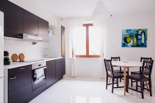kuchnia z czarnymi szafkami, stołem i krzesłami w obiekcie Zimmer & Appartements in der Gamlitzerstrasse w mieście Ehrenhausen