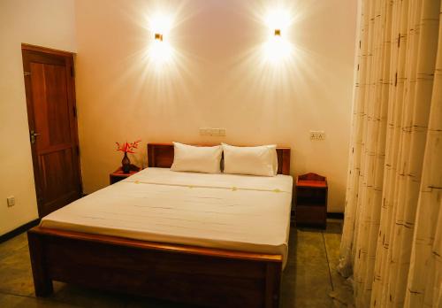 a bedroom with a bed with two lights on the wall at Paradise Beach House - 3 Bedrooms Apartment in Habaraduwa in Habaraduwa