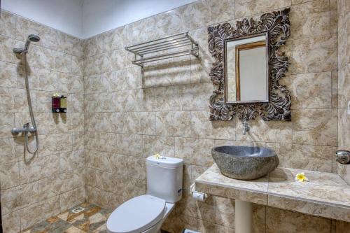 ein Badezimmer mit einem Waschbecken, einem WC und einem Spiegel in der Unterkunft Indah Guest House Nusa Penida in Nusa Penida