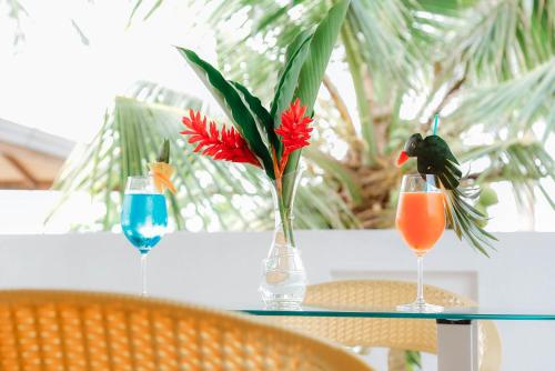 a table with two glasses and a vase with a red flower at Paradise Beach House - 3 Bedrooms Apartment in Habaraduwa in Habaraduwa