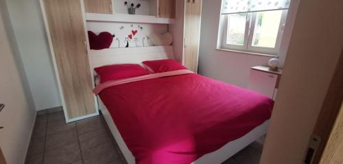 a small bedroom with a pink bed with a window at Apartment Heaven Hill in Jadranovo