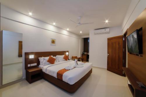 a bedroom with a large bed and a television at VEETEE MID TOWN in Kallar Vattiyar