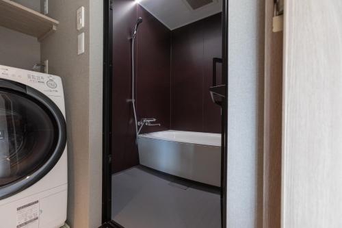 廣島的住宿－FAV HOTEL Hiroshima Heiwa Odori，带浴缸和洗衣机的浴室。