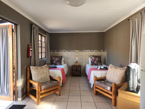 a room with two beds and two chairs and a tv at Snips Accommodation in Newcastle