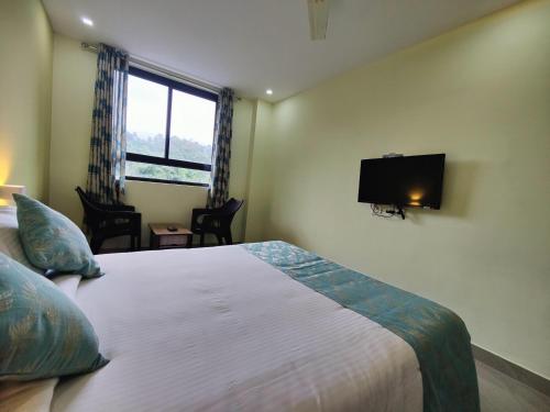 a bedroom with a bed and a flat screen tv at Munnar BnB in Munnar