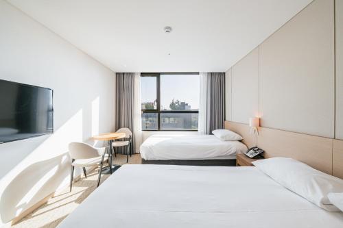 een hotelkamer met 2 bedden en een televisie bij Hotel Zinc in Seogwipo