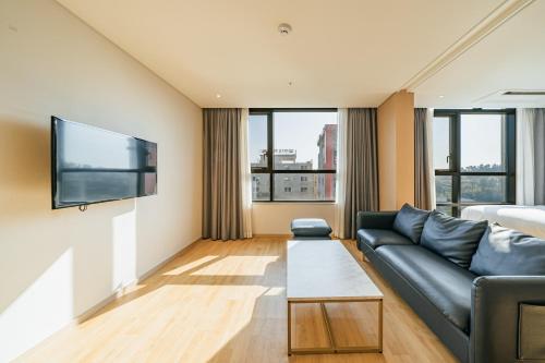 a living room with a couch and a flat screen tv at Hotel Zinc in Seogwipo