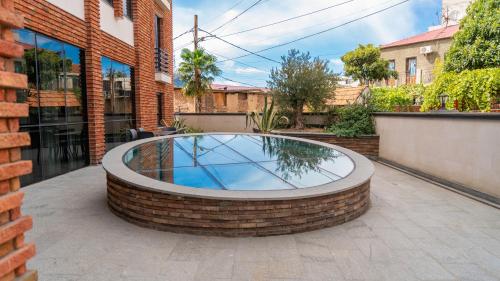 a circular pool in a brick courtyard in front of a building at Hotel Banovani in Tbilisi City