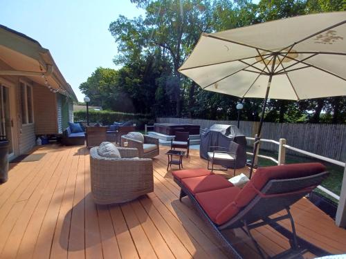a patio with chairs and an umbrella on a deck at Cozy 4BR 3BA Home- Train to NYC, USOpen, CitiField Mets, Walk to Harbor & Golf in Port Washington