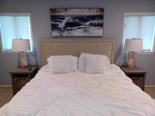 a bedroom with a white bed with two windows at Cozy 4BR 3BA Home- Train to NYC, USOpen, CitiField Mets, Walk to Harbor & Golf in Port Washington