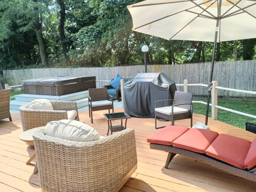 a patio with chairs and an umbrella and a grill at Cozy 4BR 3BA Home- Train to NYC, USOpen, CitiField Mets, Walk to Harbor & Golf in Port Washington