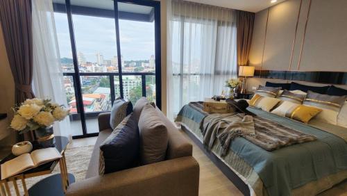a bedroom with a bed and a couch and a window at The Panora Pattaya in Pattaya South