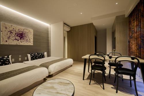 a hotel room with two beds and a table and chairs at fav HIROSHIMA HEIWAODORI in Hiroshima
