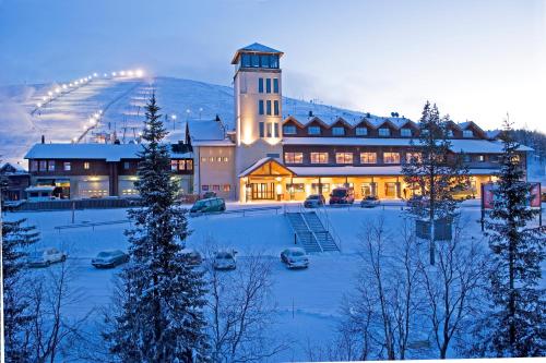 a large building with a snow covered yard in front of it at Lapland Hotels Ylläskaltio in Äkäslompolo