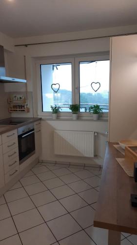 a kitchen with two windows with hearts hanging from them at Ferienwohnung Windhagen in Windhagen