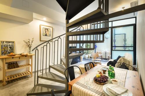 a dining room with a table and a spiral staircase at Cozy Modern 1BR Duplex Apt w Balcony Near City Center by Sea N' Rent in Tel Aviv