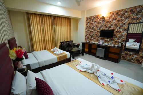 a hotel room with two beds and a television at Grand Mostafa Hotel Ababil in Sylhet