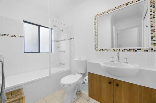 a bathroom with a toilet and a sink and a mirror at 'Little Mermaid' beach apartment best location walk to beach and restaurants - sleeps 4 in Gold Coast