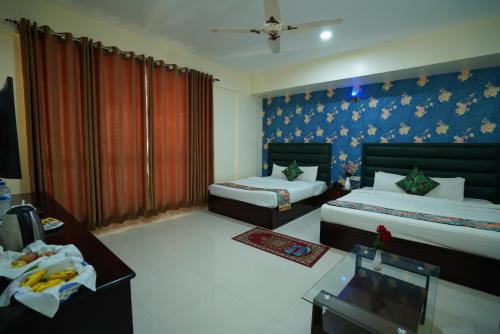 a bedroom with two beds and a blue wall at Grand Mostafa Hotel Ababil in Sylhet