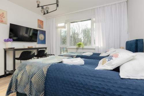 a bedroom with two beds and a desk and a television at Warsaw Batorego Studio Apartments by Renters in Warsaw