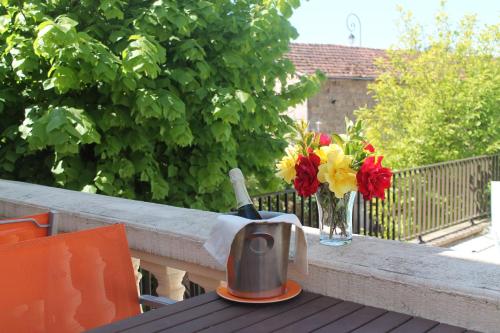 a table with a vase of flowers on a balcony at Logis Hôtel Vuillot in Cuiseaux