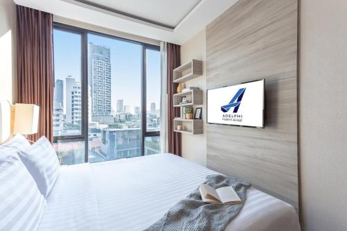 a hotel room with a bed and a tv on a wall at Adelphi Forty-Nine in Bangkok