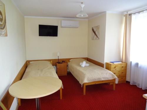 a room with two beds and a table and a tv at MADOHORA_SŁOŃCE in Zaryte