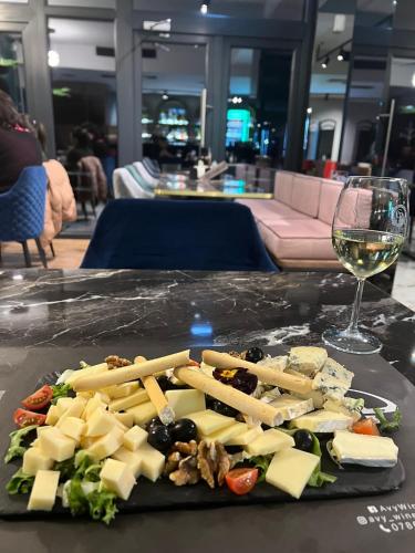 a plate of cheese and vegetables with a glass of wine at Vila Avy in Haţeg