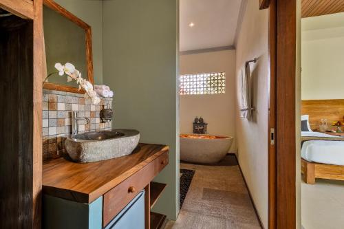 ein Badezimmer mit einem Waschbecken und einer Badewanne in der Unterkunft Kubu Rama Ubud Cottage in Ubud