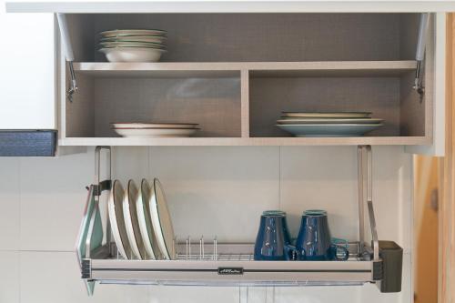 a kitchen cabinet with plates and bowls and utensils at K'STAY Sinchon in Seoul