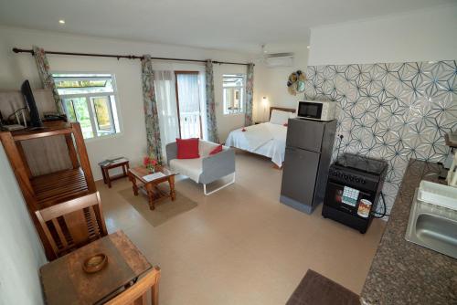 a living room with a bed and a kitchen with a stove at La Maison Hibiscus Self Catering Accommodation in Beau Vallon