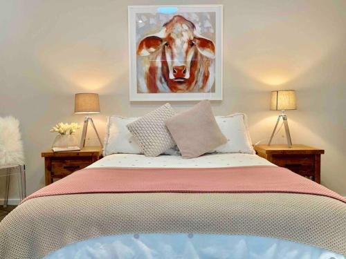 um quarto com uma cama com um quadro de uma vaca em 'TAMWORTH'S HIDDEN GEM’ 